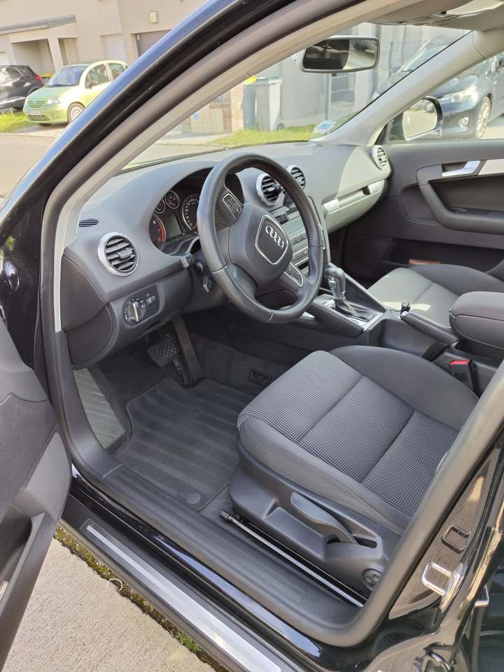 Poste de conduite d’une Audi A3 vu par la portière ouverte : siège, tapis et contre-porte
