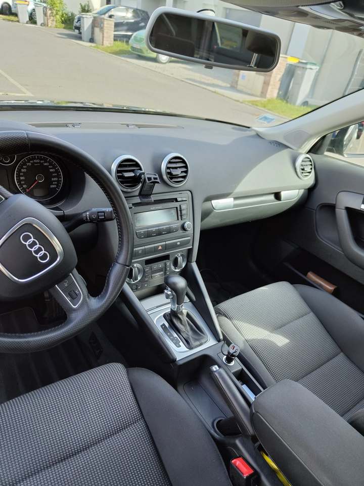 Tableau de bord, volant et console centrale d’une Audi A3, plastiques propres et sièges en tissu