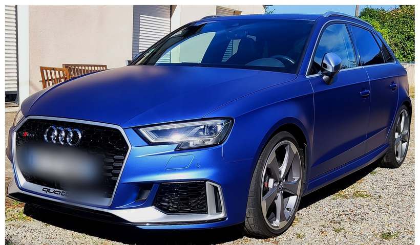 Audi RS3 Sportback bleu mat vue de trois quarts avant, jantes grises, sur une allée gravillonnée