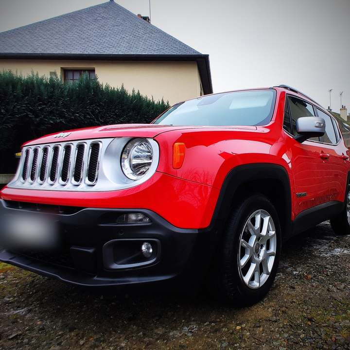 Jeep Renegade rouge vue de trois quarts avant devant une maison