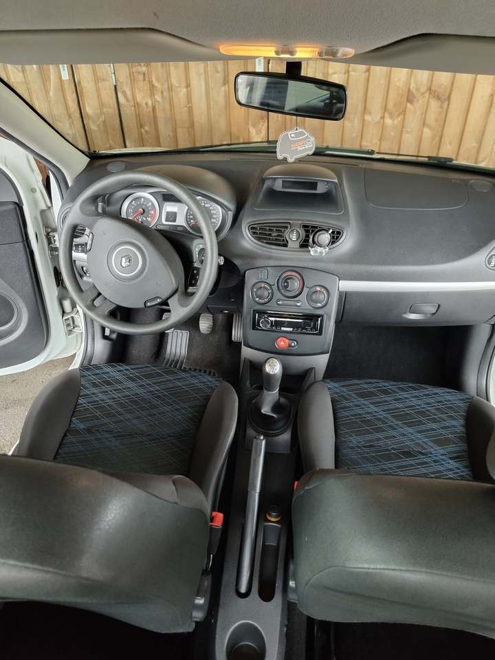 Habitacle d’une Renault Clio III vu depuis l’arrière : sièges avant en tissu, tableau de bord et console